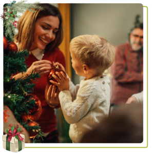 child and woman decorating Christmas tree with ornaments 