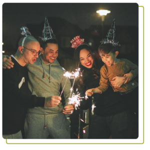 A family celebrating new years eve with party hats and sparklers.