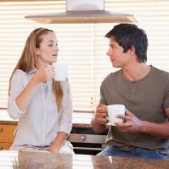 Couple talking over coffee in kitchen